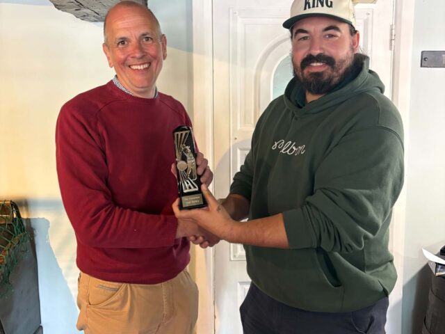 Two golf society members holding a trophy in the bar