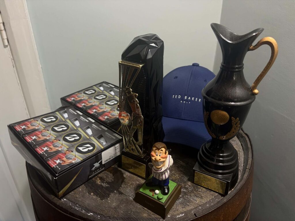 The golf society's trophies, a cap and boxes of balls on a barrel
