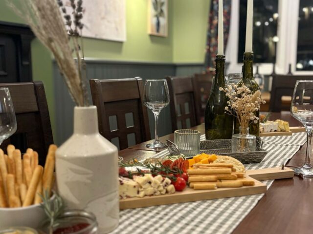 A table laid with a sharing board, wine glasses and a gingham runner