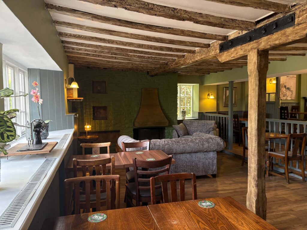 Inside the pub: beams, a fireplace, sofas and tables