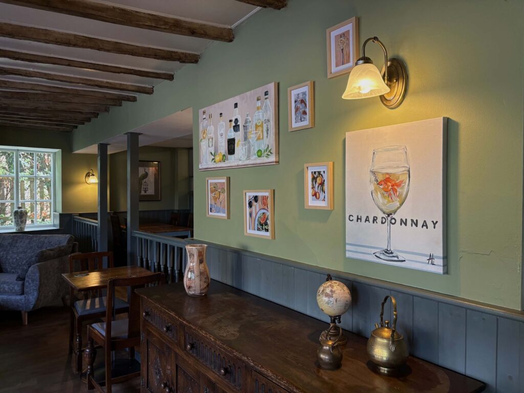 The dining room: sage green walls, framed pictures and a wall lamp