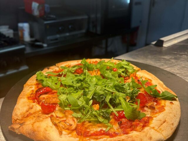 A sourdough pizza piled with rocket