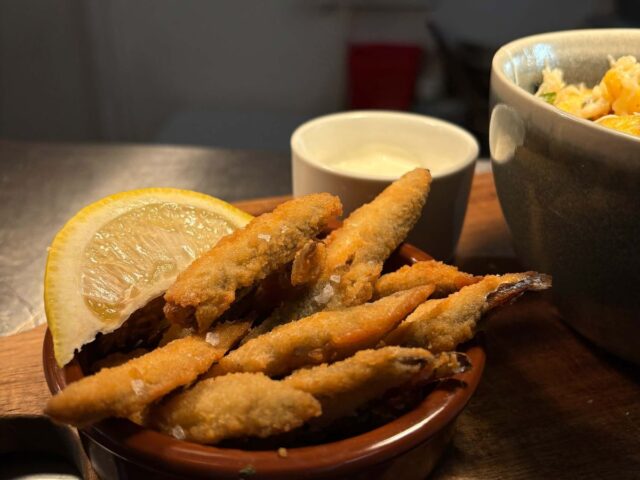 Whitebait in a dish with lemon and a pot of mayo