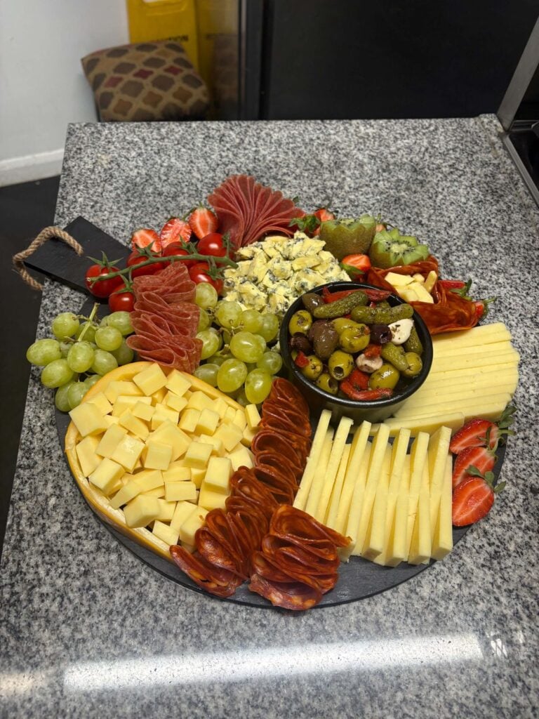 A grazing board of cheeses, cured meats, olives and grapes